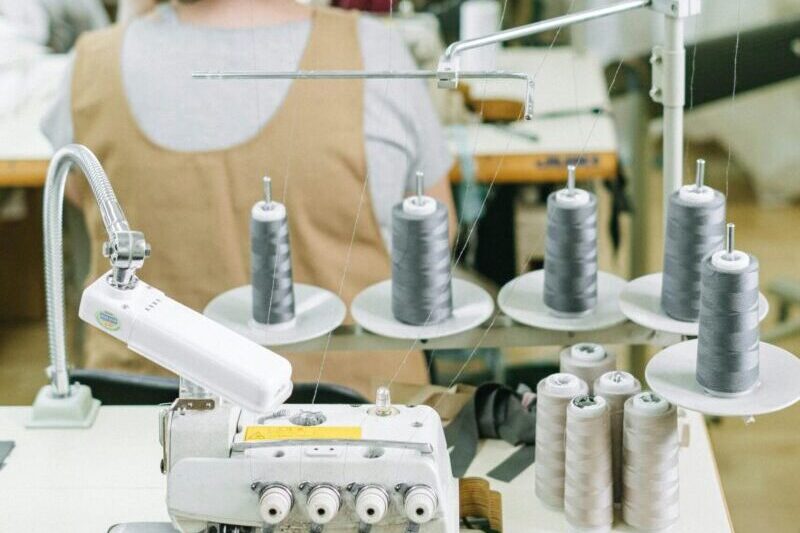 Sewing machines and workers in a textile factory, highlighting industrial manufacturing processes.