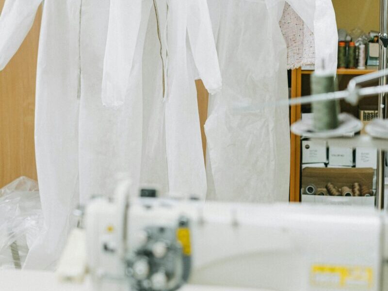 A sewing room showcasing hanging protective suits and a sewing machine.